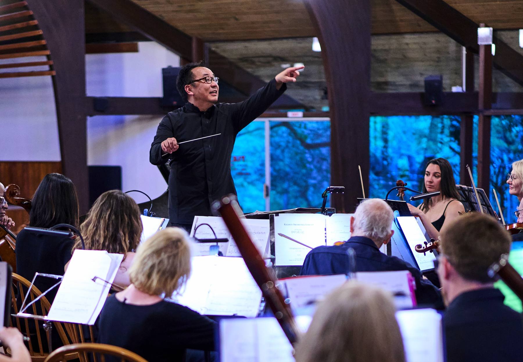 The orchestra in rehearsal, with the conductor cueing the strings and a Dvorak score open on the stand